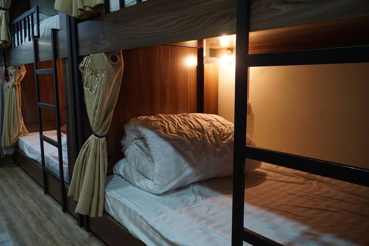A bunk bed room with wooden walls, a ladder, and a hanging robe.