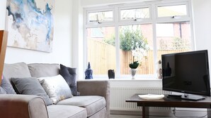 Un salon moderne avec un canapé, un téléviseur à écran plat, une grande fenêtre et une lucarne.