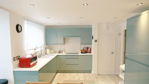 Une cuisine de taille réduite avec des meubles de couleur turquoise, un four à micro-ondes et un évier.