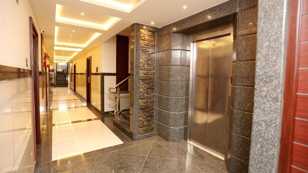 A modern hotel lobby with a marble floor, a staircase, and an elevator. - LNB Residency (Tirupati)