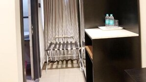 A narrow hallway with a dark wooden panel on the right, a white shelf with water bottles, and a curtain at the end. - LNB Residency (Tirupati)