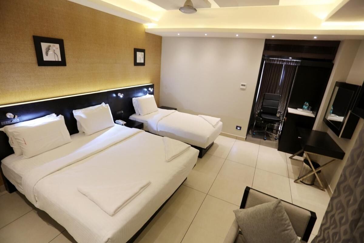 Habitación de hotel con dos camas, un escritorio, una silla y un televisor.