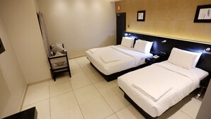 A hotel room with two beds, a bedside table, a chair, and a wall-mounted artwork. - LNB Residency (Tirupati)