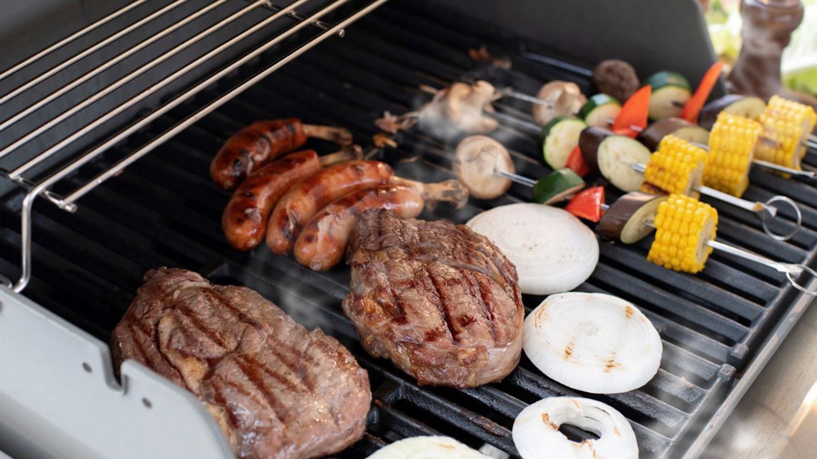 A grill with various meats and vegetables being cooked.