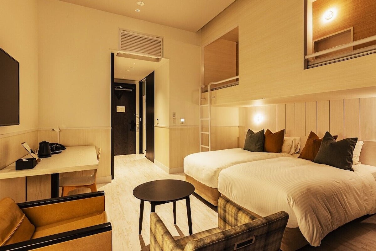 Ett hotellrum med en säng, ett skrivbord, en stol och ett litet bord.