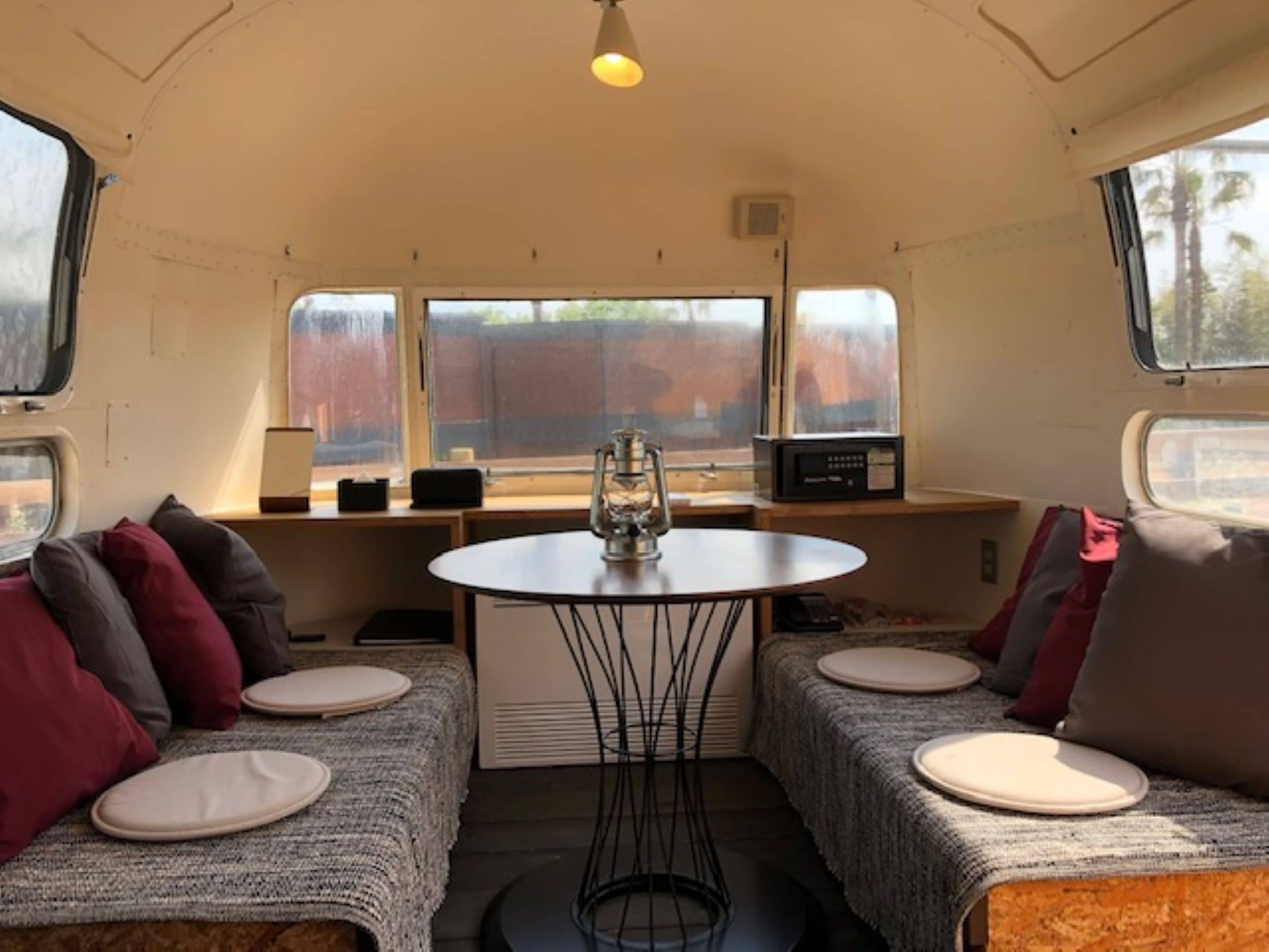 A cozy interior with two seating areas, a central table, and windows providing views.