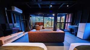 A modern hotel room with a large bed, a TV, a desk, and a view of the mountains. - THE Retreat (Iizuka)