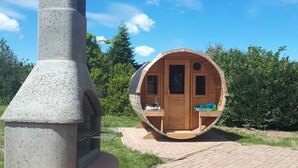 A concrete structure with a chimney, a wooden cabin with a curved roof, and a paved walkway. - Villa beach robber Rügen (Zudar)
