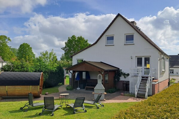Una casa a due piani con un patio, posti a sedere all'aperto e un barbecue.
