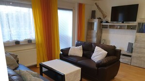 A living room with a brown leather sofa, a coffee table, and a TV on a wooden stand.