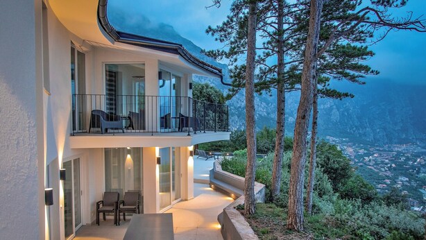 Una casa moderna con balcón que da a un paisaje montañoso.