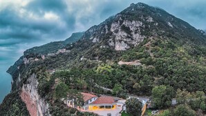 Una casa de montaña con techo de tejas rojas, rodeada de un bosque denso y con vistas a un cuerpo de agua.