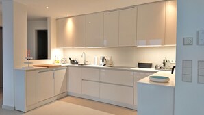 Una cocina moderna con armarios blancos, una isla central y electrodomésticos integrados.
