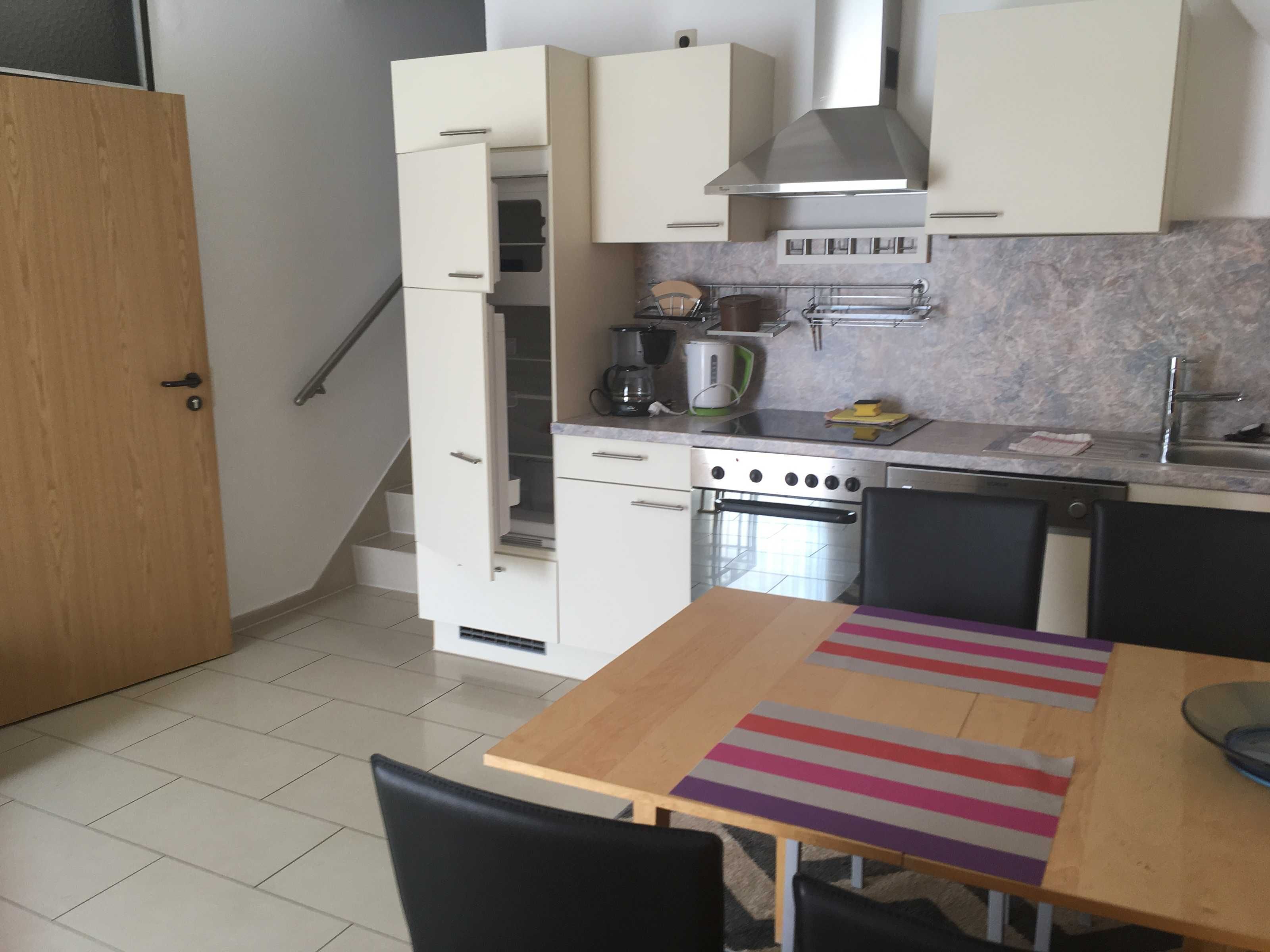 A compact kitchen with white cabinets, a stove, and a sink.
