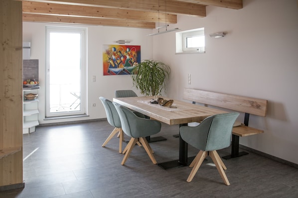 A dining area with a wooden table, four chairs, a bench, and a potted plant.