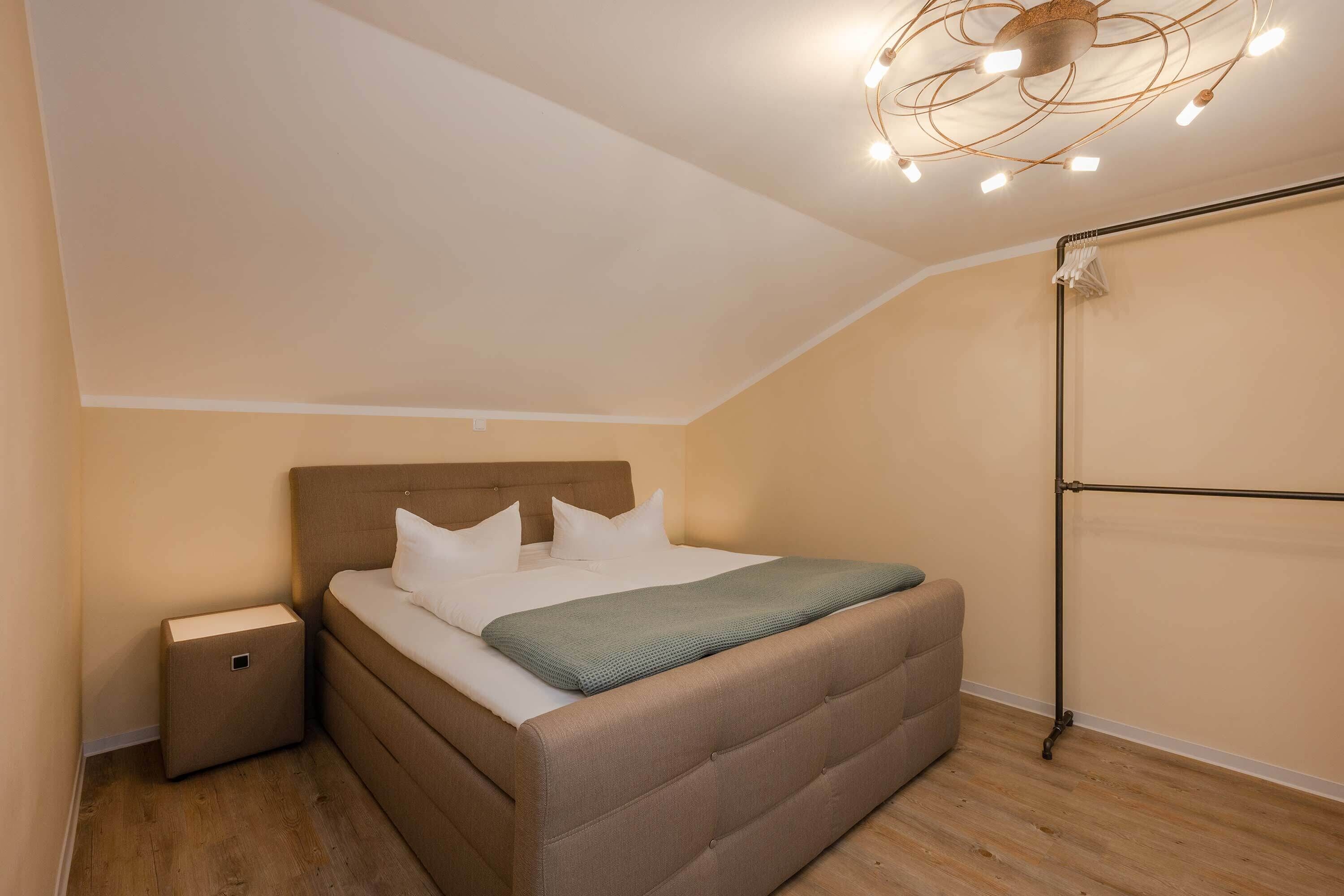A bedroom with a bed, nightstand, and a ceiling light fixture.