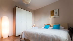 Un dormitorio con cama, armario, mesita de noche y una obra de arte en la pared.
