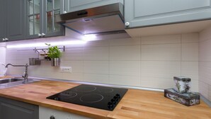 Una cocina moderna con gabinetes grises, un extractor de acero inoxidable, encimera de madera, horno empotrado y una pequeña planta en maceta.