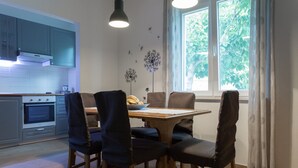 Una cocina moderna con armarios grises, una mesa de comedor con cuatro sillas y una ventana con cortinas.
