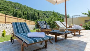 Una terraza con sillones, una mesa y una sombrilla.