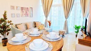 Un coin repas avec une table ronde en bois, dressée pour quatre personnes, entourée d’un canapé et d’une petite table d’appoint.