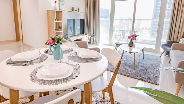 Un salon moderne avec un coin repas, de grandes fenêtres et un balcon.