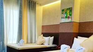 A hotel room with two beds, a small table, and a painting on the wall. - Davao Persimmon Suites (Davao)
