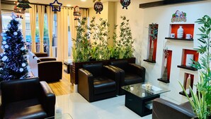 A modern living room with black leather sofas, a glass coffee table, and a Christmas tree. - Davao Persimmon Suites (Davao)
