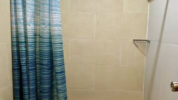 Een kleine badkamer met een douche, toilet en wastafel.