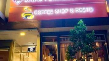 Un edificio con un letrero que dice 'Davao Persimmon Suites' y una cafetería.