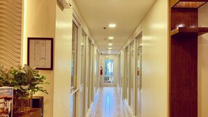 A hotel corridor with a wooden floor, glass doors, and a plant on the left. - Davao Persimmon Suites (Davao)