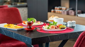 Una mesa de desayuno dispuesta con platos de comida, una taza de té y aderezos.