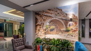 Un vestíbulo con un mural de piedra, asientos cómodos y plantas en macetas.