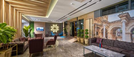 A modern lobby with a marble floor, plush seating, and a large wall mural.