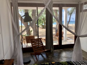 A room with a view of a beach, featuring a hammock, wooden chairs, and a table. - Liquid Dive Adventures (Tofo)