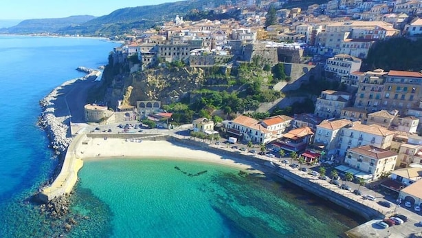 Une ville côtière dotée d’une plage de sable, d’eaux d’un bleu limpide et de bâtiments qui bordent le rivage.