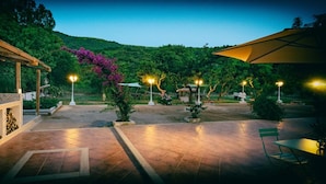 Un espace extérieur aménagé en terrasse, doté d’un sol carrelé, d’une pergola et d’un coin salon avec une table et des chaises.