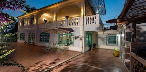 A two-story building with a covered patio area, outdoor seating, and a balcony.