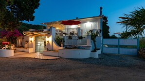 Une maison à deux étages avec un porche couvert, un parasol rouge et une allée gravillonnée.