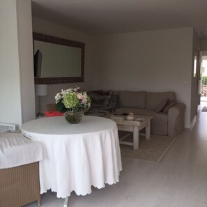 A living room with a round table, a sofa, a mirror, and a vase of flowers. - High Standing Apartment (Gassin)