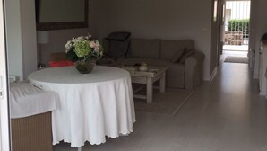 A living room with a round table, a sofa, and a dining area.