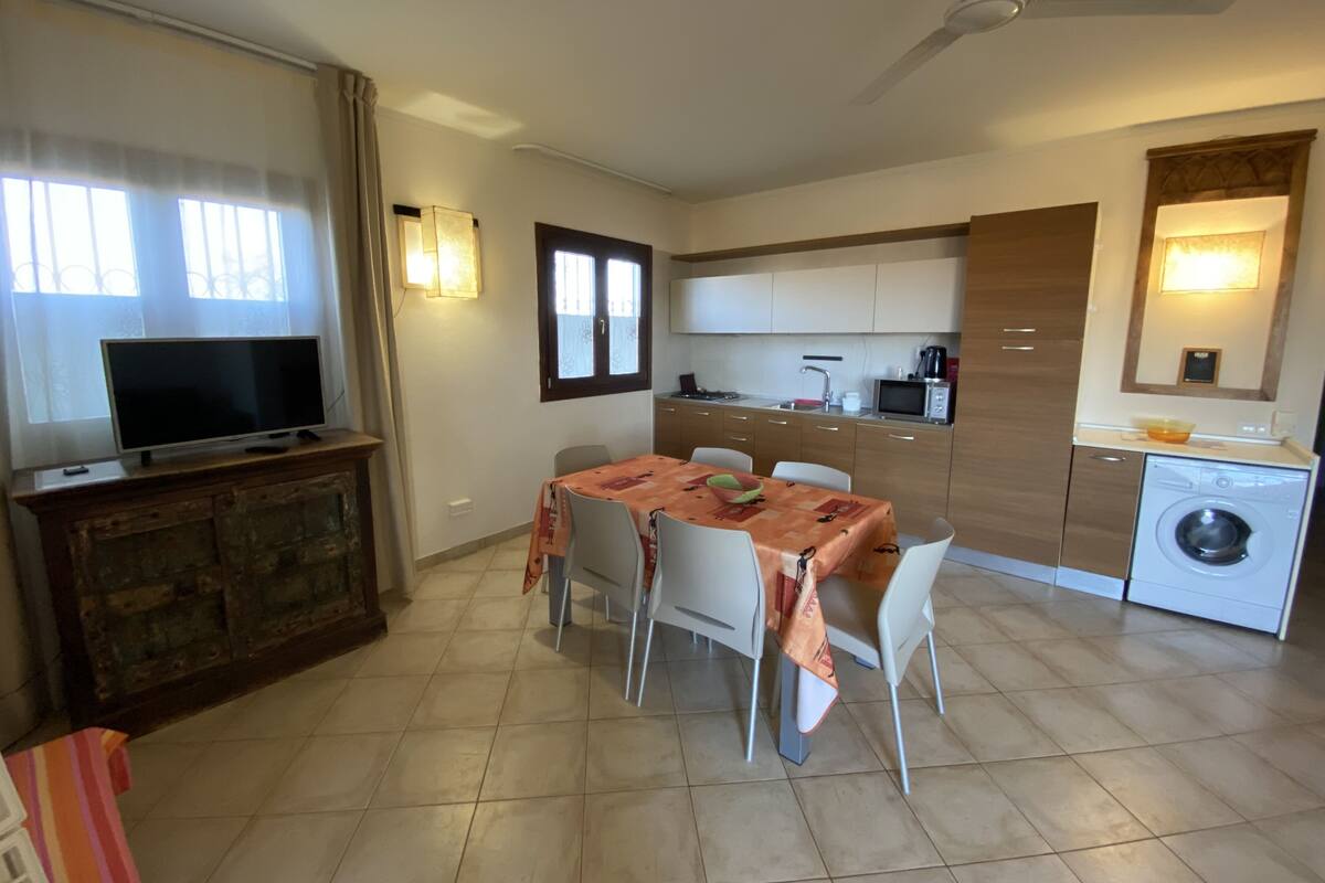 Een knus woongedeelte met een eethoek, kitchenette en een televisie op een houten kast.