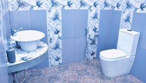 A bathroom with a freestanding sink, toilet, and shower. - Hotel Aram (Unawatuna)
