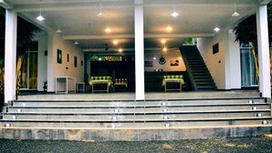 A building with a staircase leading to a covered area with tables and chairs. - Hotel Aram (Unawatuna)
