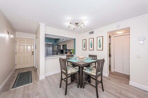 Zona pranzo con tavolo e sedie, una cucina sullo sfondo e un lampadario al soffitto.