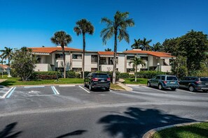 A multi-story building with a red-tiled roof, parking spaces, and palm trees. - Waterfront 2BR/2BA Isla Del Sol condo with pool, hot tub, balcony, and views. (St Petersburg)