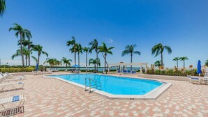 A swimming pool with lounge chairs and palm trees. - Waterfront 2BR/2BA Isla Del Sol condo with pool, hot tub, balcony, and views. (St Petersburg)