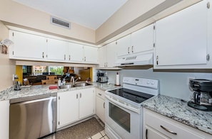 A modern kitchen with white cabinets, stainless steel appliances, and a granite countertop.