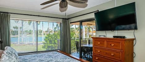 Una habitación de hotel con cama, cómoda de madera, televisor y ventilador de techo.