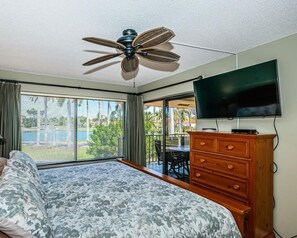 Relax in this serene hotel room featuring a large bed, dresser, and flat-screen TV.